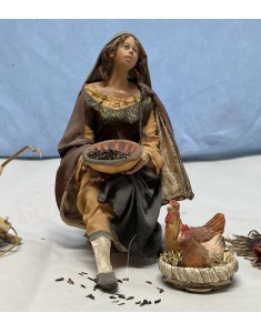 Donna seduta che da da mangiare alle galline capolavoro di Angela Tripi che realizza statuine del presepe da collezione