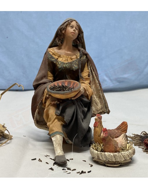 Donna seduta che da da mangiare alle galline capolavoro di Angela Tripi che realizza statuine del presepe da collezione
